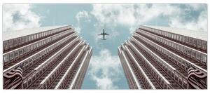 Obraz lietadla medzi budovami (120x50 cm)