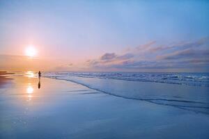 Umelecká fotografie Person walking on beach at sunrise, Shannon Fagan, (40 x 26.7 cm)