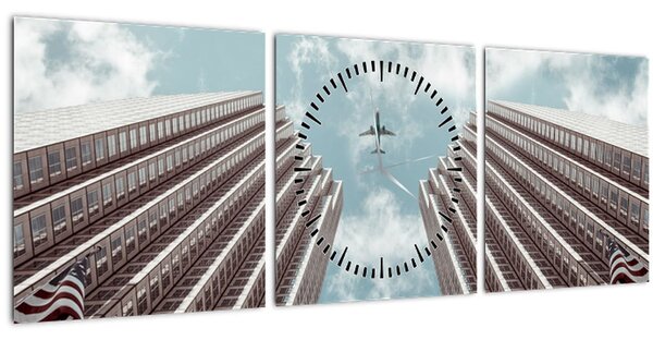 Obraz lietadla medzi budovami (s hodinami) (90x30 cm)