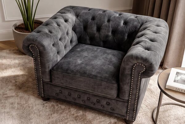 Estila Dizajnové sivé kreslo Chesterfield so zamatovým poťahom s prešívaním s okrúhlymi gombíkmi a zarolovanou opierkou 109 cm